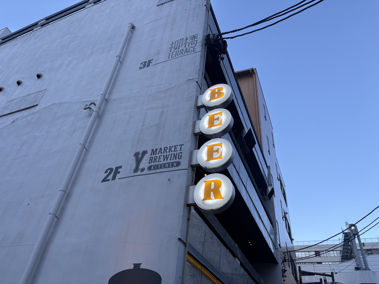 Y.MARKET BREWINGの壁面サイン。3F柳橋TERRACE、2Fワイマーケットブルーイングキッチンの表示とBEERの縦看板