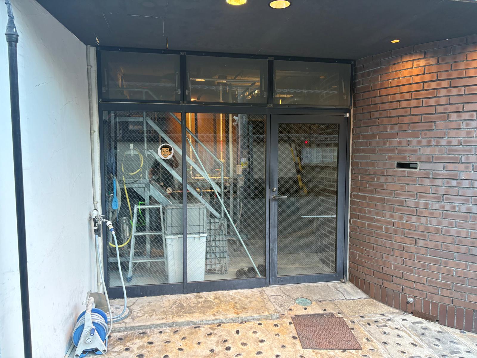 Y.MARKET BREWINGの1階醸造所をガラス越しに見たところ。配管やタンク、作業スペースが見える