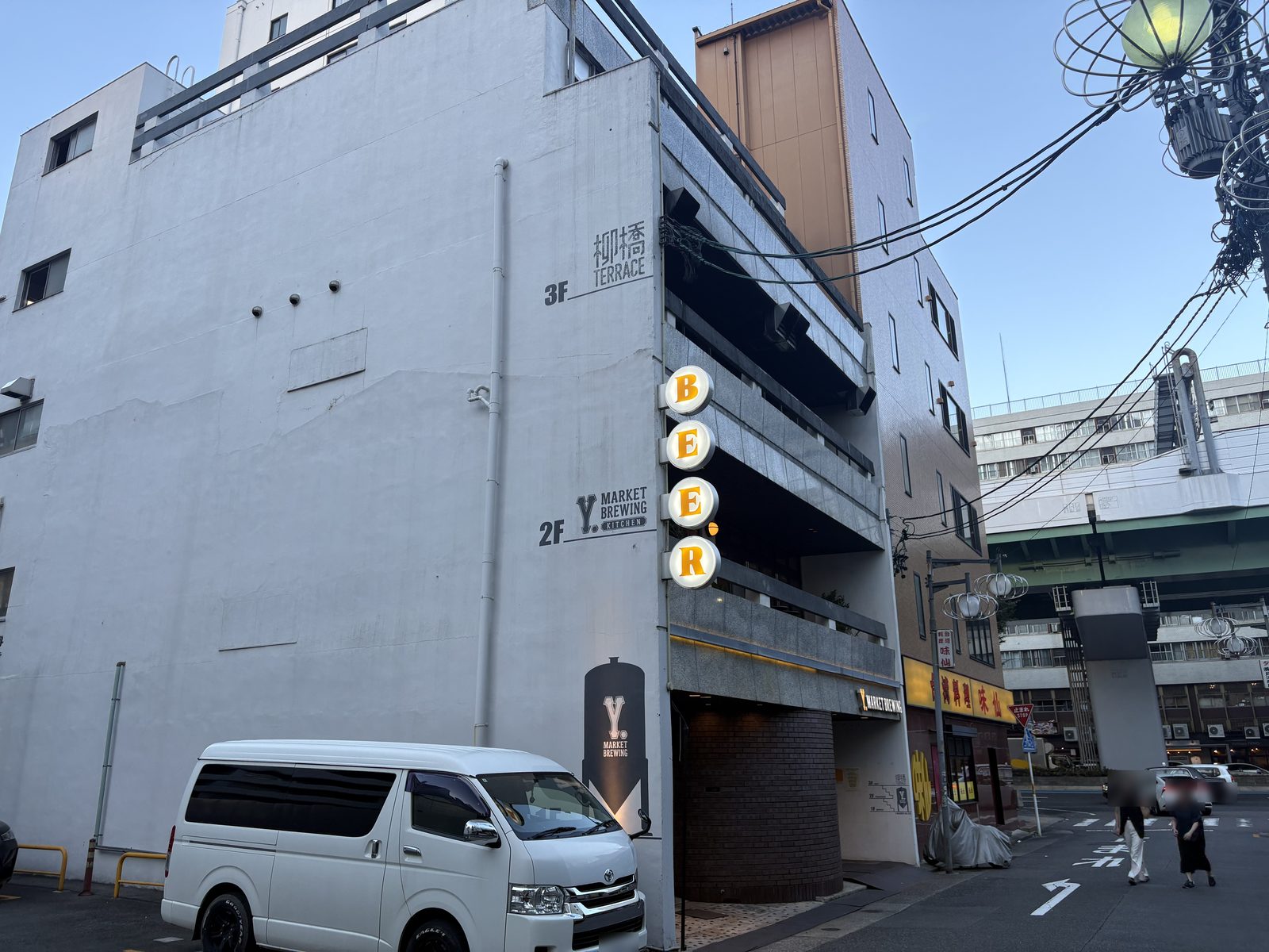 名古屋・柳橋のY.MARKET BREWINGの建物外観。夕暮れの空にBEERの縦看板が灯っている