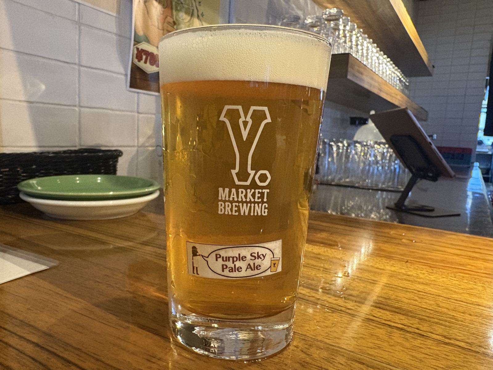 Y.MARKET BREWINGで1杯目に飲んだパープルスカイペールエール。黄金色でロゴ入りグラスに注がれている